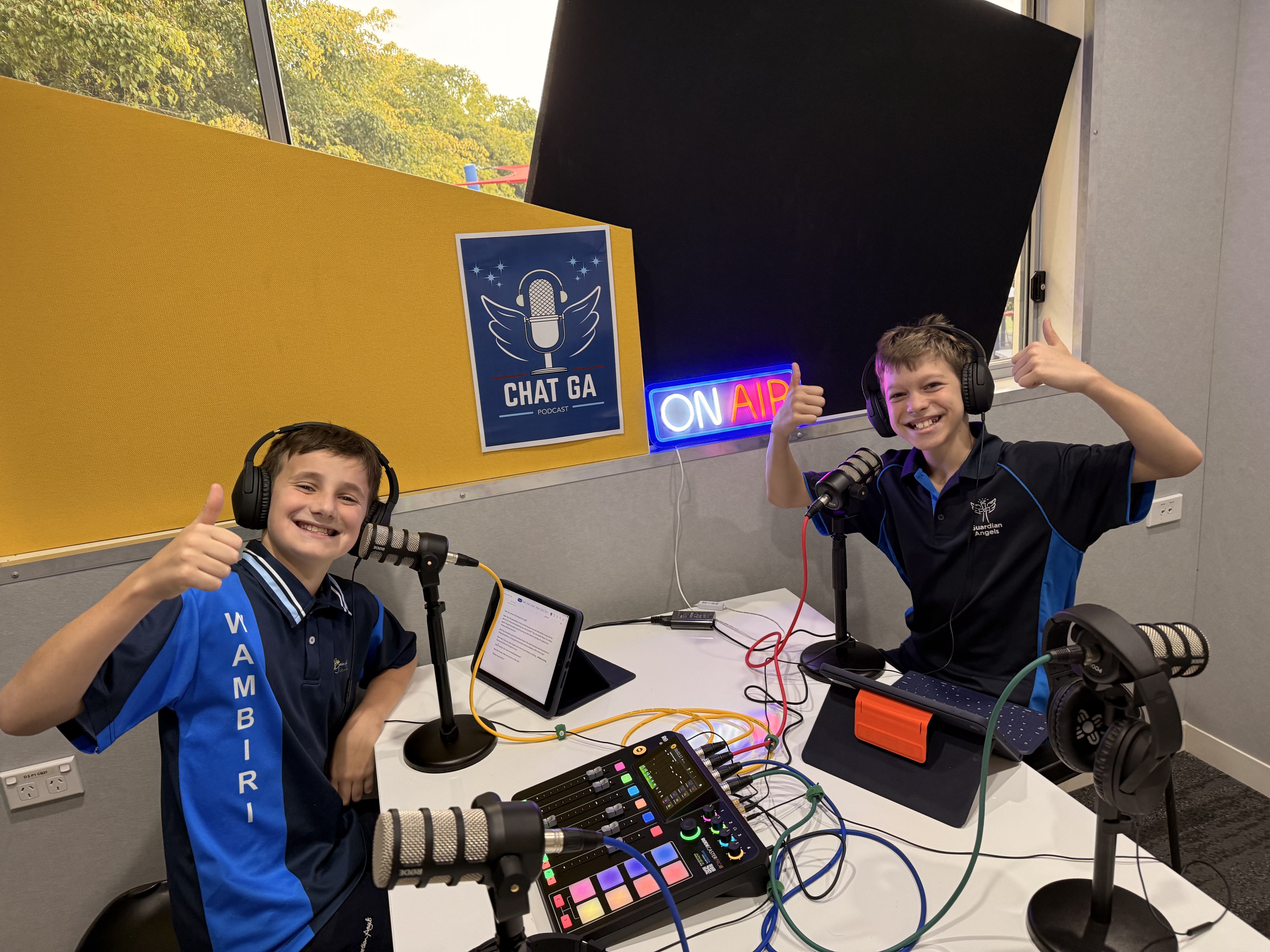 Students participating in a school podcast recording giving thumbs up while wearing headphones and using microphones