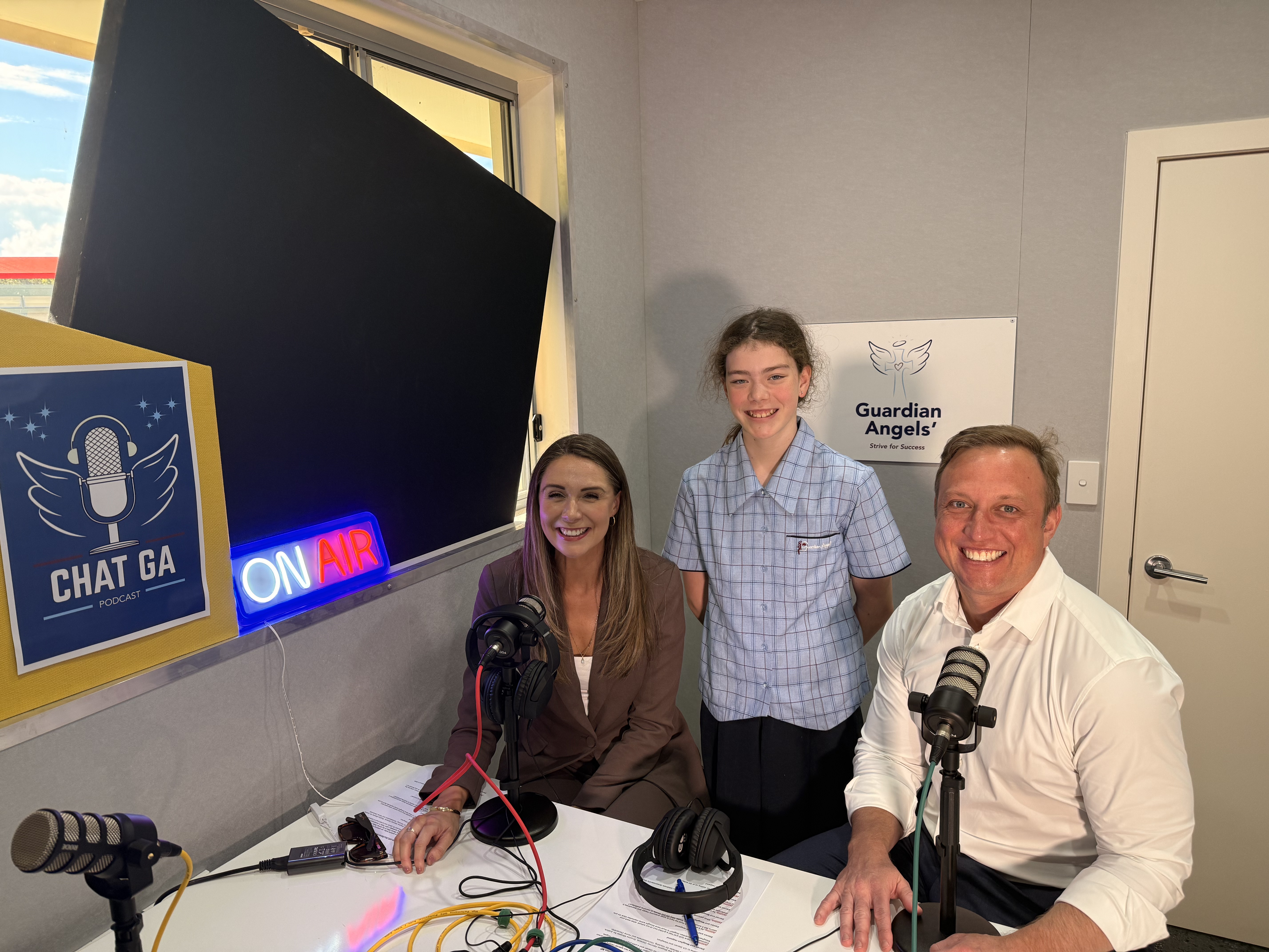 Student with MP recording a school podcast interview in a media studio with microphones and audio equipment