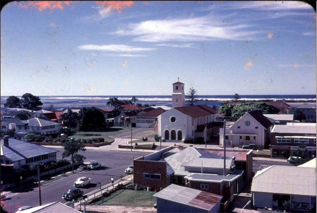 Historic coastal parish with church, surrounding buildings and nearby ocean reflecting early Catholic community setting